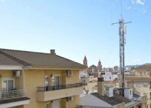 Imatge que mostra un edifici d'habitatges amb una gran antena de telecomunicacions al terrat, il·lustrant la proximitat a radiacions per a un estudi de Feng Shui.